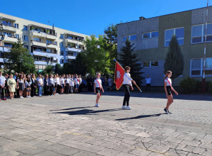 Uczniowie wyprowadzają sztandar szkoły na placu apelowym.